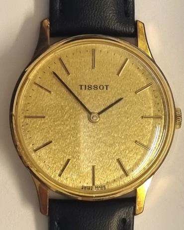 Tissot manual wind wrist watch in a gold plated case with a stainless steel back on a black leather strap with gilt buckle. Signed champagne coloured textured dial with black and gilt baton hour markers and matching black hands. Swiss made signed Tissot calibre 2541 jewelled lever movement numbered 20714 with signed stainless steel back numbered 41158.