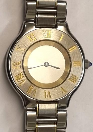 Swiss made mid-size Cartier Le Must quartz wrist watch in a bi-colour polished and satin finished case with matching integral bracelet. Silvered dial with blued steel hands and outer steel bezel displaying gilt inset Roman hours. Swiss signed screw down water resistant case back together with gem set crown.