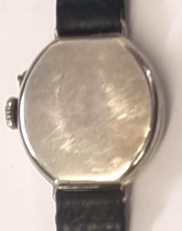 Swiss tonneau shaped Officers Style Trench wrist watch in a silver case with London import hallmark for c1923 on a black leather strap with silvered buckle. Crown manual wind with separate pin set time change. White enamelled dial with black Roman hours and minute track and blued steel hands. Swiss jewelled lever movement with case back by 'G.D' and numbered 366741 2.