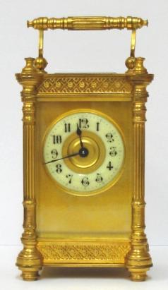 French gilt brass and 5 glass, 8 day carriage clock time piece circa 1900, maker unknown. Ornate casework with Corinthian style columns and matching carrying handle, together with open fretwork panels at top and bottom on each side. Chamfered glass panels throughout and gilt matt mask to the circular ivorine dial which has black Gothic hours and blued steel hands and a central gilt disk. Plain unmarked brass movement with contemporary cylinder escapement. Height - 6" Width - 3.25" Depth - 2.75".