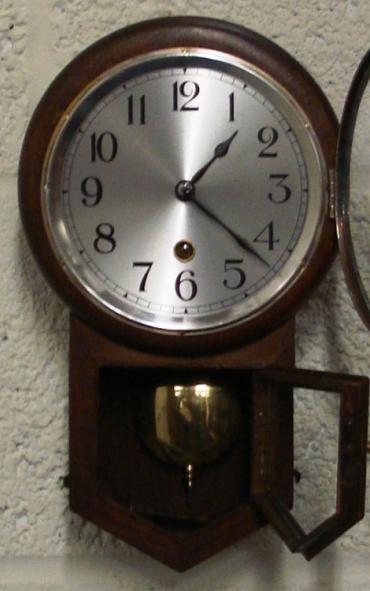 German dark oak drop dial cased wall clock by H.A.C. of Wurttemberg. Brass bezel with convex glass over a silvered dial with black arabic numerals and black painted steel hands. Separate opening window to visible brass pendulum and key holder. H.A.C. paper label on clock back with number #2609.