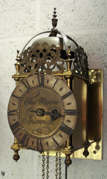 English reproduction 30 hour lantern clock signed to the dial 'Thos. Moore, Ipswich'. Brass and steel case with silvered chapter ring with black roman hours and blued steel hour hand. The good quality brass 30 hour movement has a single iron weight and brass and steel pendulum and strikes the hours on a bell.  Dimensions: Height - 15.5", Width - 6.5", Depth 7.5".
