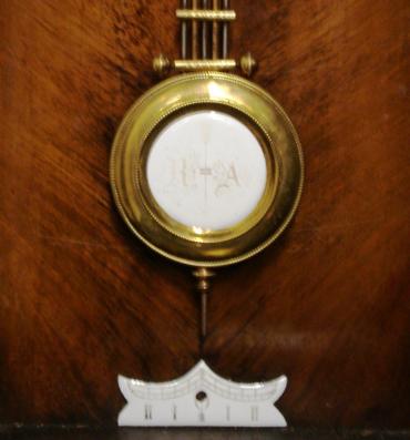 German 8 day wall clock circa 1880, spring driven pendulum movement housed in a pine case with a decorative turned finial and side columns together with applied mouldings. White enamel and brass dial with black roman hour markers and black steel hands, the dial signed 'Fattorini & Sons, Bradford' and 'Made in Baden'. The movement has a banjo style pendulum and there is an enamel pendulum regulation plate at the case bottom. Unusually the movement does not strike the hours or half hours, but plays an air on a musical box mechanism on the hour 