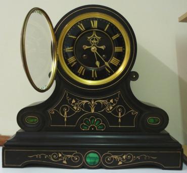 Heavy 8 day scrolling black marble cased mantel clock with malachite inlay and carved and gilded floral motif decoration circa 1890. Circular gilt bezel with flat chamfered glass over a black dial with gilt roman hours and gilt hands, together with the Brocot visible escapement below 12 o'clock and slow/fast adjuster at the dial top. French brass spring driven pendulum regulated movement striking on a bell, maker unknown, but stamped on the back plate #274.