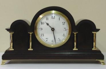 French 8 day mantel clock timepiece in an impressive triple arched dark mahogany case with gilt brass columns and bracket feet. Gilt brass bezel with convex glass over a white enamel dial with black Arabic hours and black steel hands. Brass drum case movement maker unknown stamped 'France' with a good quality replacement lever escapement platform and a captive winding key.    Dimensions: Height - 11", width - 6", depth - 3.5".
