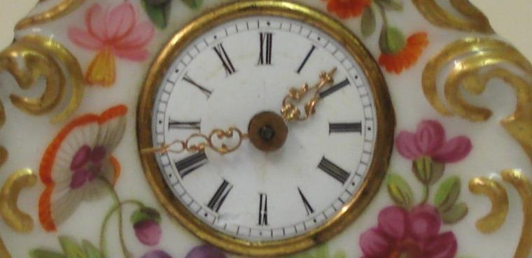 Good quality porcelain cased bedside or mantel clock with applied gilding and enamel flower decoration throughout. White enamel dial with slight damage, black roman hours and ornate gilt metal hands. Miniature brass spring driven late 19th century 8 day movement, maker unknown, with gilt  pendulum.