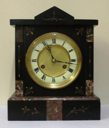 German 8 day slate and marble cased mantel clock circa 1900 by Jungans. Architectural square case with decorative engraved decoration with gilt infill. Gilt circular bezel with flat chamfered glass and white enamel chapter ring with a matt gilt interior together with black roman hours and ornate blued steel hands. Good quality spring driven, gong striking movement, regulated by a pendulum and with the Junguns touch mark.