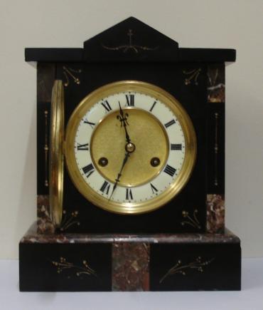 German 8 day slate and marble cased mantel clock circa 1900 by Jungans. Architectural square case with decorative engraved decoration with gilt infill. Gilt circular bezel with flat chamfered glass and white enamel chapter ring with a matt gilt interior together with black roman hours and ornate blued steel hands. Good quality spring driven, gong striking movement, regulated by a pendulum and with the Junguns touch mark.