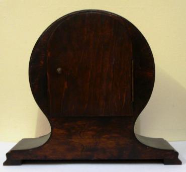 8 day dark stained oak and pine cased mantel clock circa 1920. Balloon shaped case with applied decorative moulding. Circular gilt bezel with convex glass, silvered dial with black arabic hours and black steel hands and strike / silent selection at 3 o/c. Square brass pendulum regulated, spring driven, gong striking movement, maker unknown.