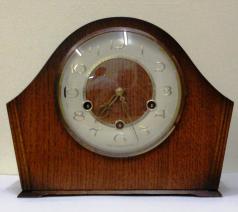English 8 day oak veneer cased mantel clock circa 1950 by Smiths. Angular round topped case with delicate side moulding and a circular brass bezel with convex glass over an ivory coloured chapter ring. Gilt arabic hours and fretwork hands and Chime / Silent control at 9 o/c. Good quality pendulum regulated, spring driven, rod striking brass movement with decorative engine turning and stamped '-Smiths-, Made in Great Britain, Smiths English Clocks Ltd.'. 