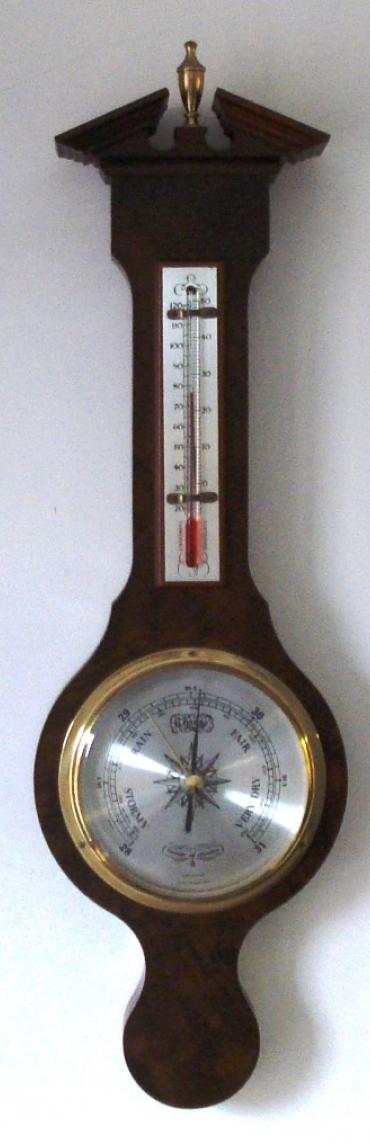 Modern Comitti of London compensated barometer in a walnut veneer case with brass finial. Circular gilt brass bezel over a silvered dial with black painted dual pressure index and a separate alcohol Centigrade and Fahrenheit thermometer.