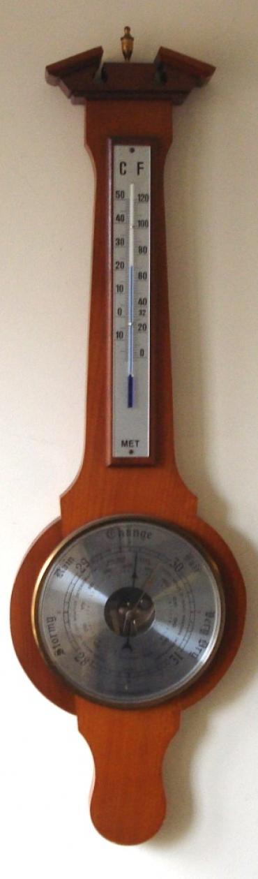 Modern Weathermaster aneroid barometer in a wood veneer case with brass finial. Circular gilt brass bezel over a silvered dial with black painted dual pressure index and a visible action. Separate alcohol Centigrade and Fahrenheit thermometer.
