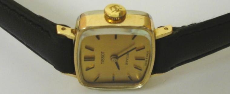 Ladies Tissot Stylist gold plated cased manual wind wrist watch on a black leather strap with gilt buckle. Matt gilt dial with black baton hour markers and matching black hands. Swiss signed Tissot 17 jewel movement numbered #12738037 with stainless steel  case back numbered 19182 - 03.