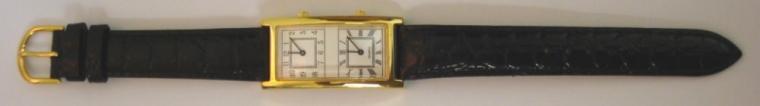 Modern quartz dual time wrist watch in as new condition. Gold plated case with stainless steel back on a black leather strap and gilt buckle. White dial with two independent time displays one with black roman hour markers and the other arabic hours, both with black coloured hands.