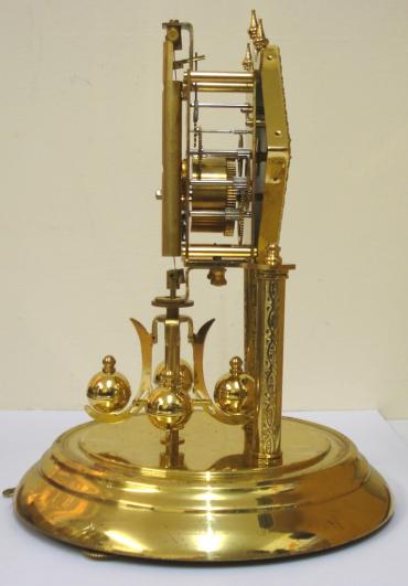 German 400 day Anniversary time piece maker unknown. Glass dome over triple stepped, level adjustment base with two engraved movement support columns. Diamond shaped gilt bezel over silvered engine turned dial plate with black arabic hours and matching black  hands. Standard brass 'anniversary' going movement with suspended oscillating slow / fast adjustable pendulum and base located locking mechanism for transportation.