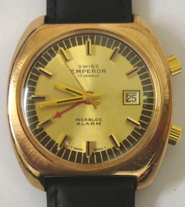 Swiss Emperor alarm wrist watch in a gold plated case with stainless steel back and secondary dust cover, on a black leather strap with gilt buckle. Gilt dial with black minute track and baton hour markers, gilt luminous insert hands and sweep seconds. Red alarm pointer hand and date display at 3 o/c. Swiss 17 jewel incabloc manual wind movement.