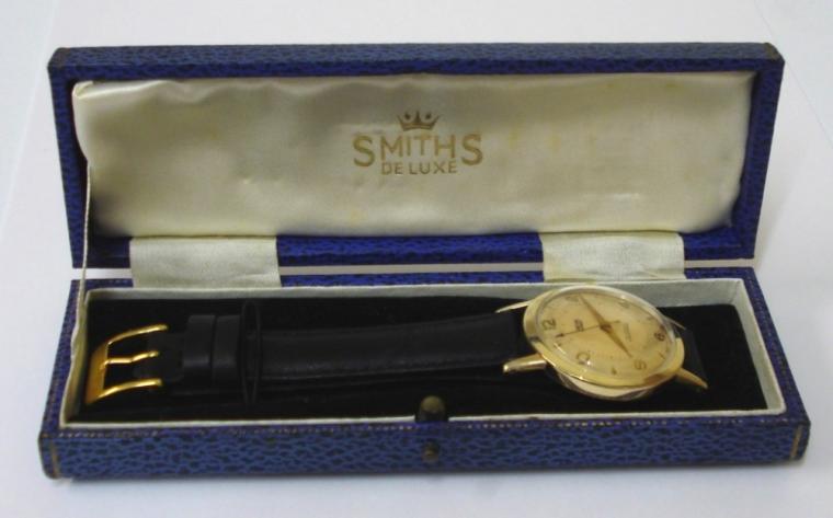Smiths Everest manual wind presentation wrist watch in a 9ct gold case on a black leather strap with gilt buckle. Champagne dial with gilt arabic and baton hour markers and matching gilt hands with red tipped sweep seconds. Smiths 19 jewel calibre 0104 movement with snap on case back hallmarked for London 1961 and inscribed to Mr A LEWIS for 25 years with Smiths - February 1963 and with original fitted box.