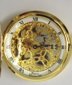 New gold plated full hunter pocket watch by the Rapport Company complete with all paperwork and box. Top wind and time change mechanical skeletonised movement with white chapter ring, black roman hour markers and ornate black painted hands. Unusual casework - first depression opens the front face time display and a second depression opens the back plate.
