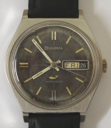 Bulova automatic wrist watch in a stainless steel case on a black leather strap with silver buckle. Aged dark blue dial with silvered baton hour markers and matching hands with sweep seconds hand and day / date display at 3 o/c. Swiss made Bulova calibre 11ANACB 17 jewel automatic movement circa 1965, with screw on case back numbered M9 G971526.