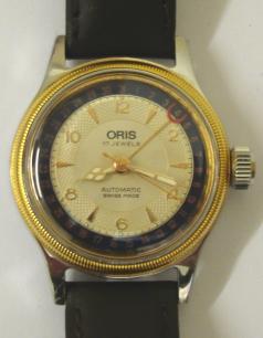 Oris 7400 BC All Stainless Steel mid size automatic wrist watch in a stainless steel case on a brown leather strap with gilt buckle. Gold plated bezel above a silvered dial with gilt baton and arabic hour markers and matching gilt luminous insert hands with sweep seconds hand. Red tipped date pointer hand indicating on an outer dark blue date track. Swiss made Oris 574 17 jewel incabloc movement with screw on case back, water resistant to 3 bar / 30 metres.
