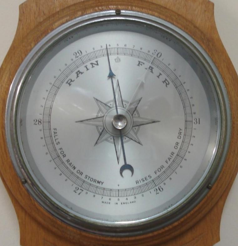 English aneroid barometer in a light oak solid wood carved and moulded case circa 1930s. Circular chromed bezel with chamfered glass over a silvered dial with black painted pressure index, blued steel pressure indicator and silvered history pointer. Separate red alcohol Fahrenheit and Centigrade thermometer.  Dimensions: - Height 19.5", width 7", depth 3".