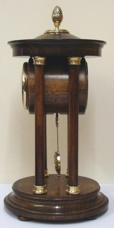 German 8 day Portico time piece by the H.A.C. clock company of Wurttemberg circa 1900. Impressive brass finial topped dark stained wooden casework with turned support pillars and brass end pieces on a circular base with bun feet. Gilt brass bezel with convex glass over a floral decorated dial with arabic hours and black hands. Unmarked drum shaped brass spring driven pendulum regulated movement.  Dimensions: Height - 13", Width - 6.5", Depth - 6.5".