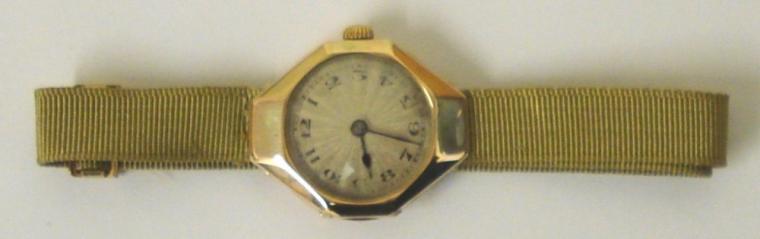 Ladies vintage Rolex manual wind wrist watch in an octagonal 9ct gold case on a gold coloured fabric strap with gilt fastening. Silvered radial dial with black Arabic hour markers and blued steel hands. Signed Rolex jewelled lever movement with Rolex case numbered #1158006 and import hallmarked for London circa 1921.