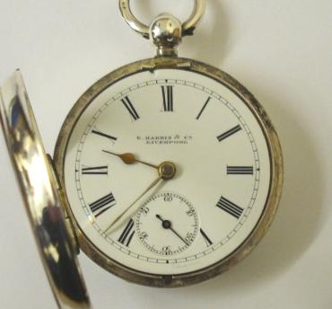 English lever silver cased pocket watch by E.Harris of Liverpool with Birmingham hallmark for 1892. Key wind and time change, white enamel dial with black Roman hours and gilt spear and shaft hands. Engraved back plate signed and numbered #226332 with engraved cock piece and jewelled end stone.