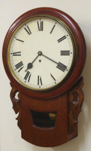 English 8 day fusee wall clock time piece, maker unknown. Original mahogany dial surround mounted on a replacement decoratively carved drop dial back case. Brass bezel with flat glass over an ivory painted dial with black Roman hours and black steel hands. Extended drop dial case with lower visible pendulum and side movement access windows. Good quality brass spring driven pendulum regulated fusee movement circa 1860.  Dimensions: Height - 23", Width - 15", Depth 7".
