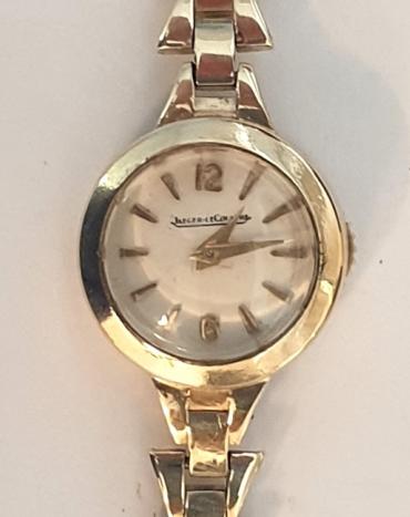 Ladies Swiss Jaeger LeCoultre manual wind wrist watch in a 9ct gold case with integral 9ct gold bracelet hallmarked for London circa 1961. Signed silvered dial with gilt hour markers and matching gilt hands. Signed jewelled lever movement numbered #49836 with back wind and time change function.