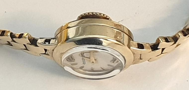 Ladies Swiss Jaeger LeCoultre manual wind wrist watch in a 9ct gold case with integral 9ct gold bracelet hallmarked for London circa 1961. Signed silvered dial with gilt hour markers and matching gilt hands. Signed jewelled lever movement numbered #49836 with back wind and time change function. 