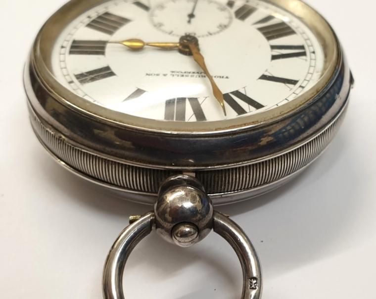 Large English silver cased pocket watch by William Ehrhardt of Birmingham, retailed by Thos Russell & Son, Liverpool, the 'WE' made case hallmarked for Birmingham 1919, and numbered 755102. Key wind and time change with retail signed white enamel dial with black Roman hours and gilt hands and subsidiary seconds dial. Plain back plate also numbered 755102 with plain cock piece, going barrel movement with bi-metallic jewelled balance.