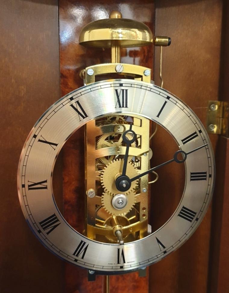 New German 8 day wall clock by Billib with passing strike on a bell. Burr walnut veneer case with curved glass front over a key wound weight driven pendulum regulated exposed skeletonised movement, with silvered chapter ring and black Roman hours with black painted hands.    Dimensions: Height - 37", Width - 9", Depth - 6".