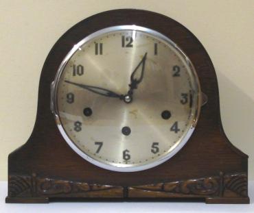 German 8 day oak veneer cased triple chime mantel clock circa 1930. Round topped hump back case with decorative front moulding and a circular chrome bezel with convex glass over a silvered dial. Black arabic hours and fretwork hands and Chime Selection (Westminster, Whittington or St.Michael) / Silent control at 3 o/c. Good quality pendulum regulated, spring driven, rod striking brass movement  stamped 'Patent No 421434, Other Patents Pending' and 'Foreign'.