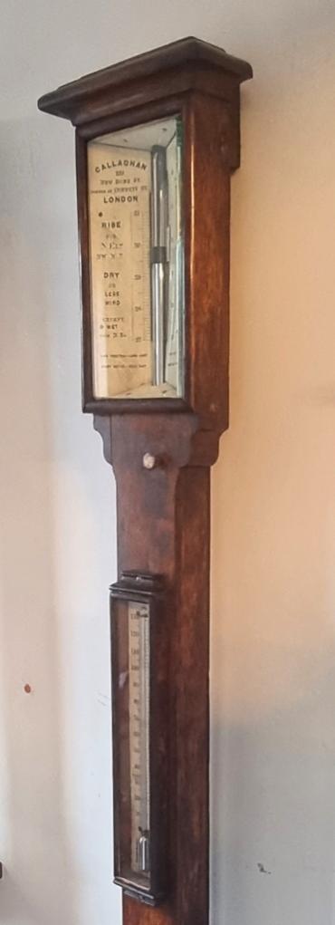 English oak cased mercury barometer and thermometer, circa 1860 by Callaghan of New Bond Street, London. Dark oak mounted flat glass over a white angled dial plate with black inches of mercury pressure indexes and predictive text. Lower oak mounted mercury thermometer displaying temperature in both Fahrenheit and Centigrade.